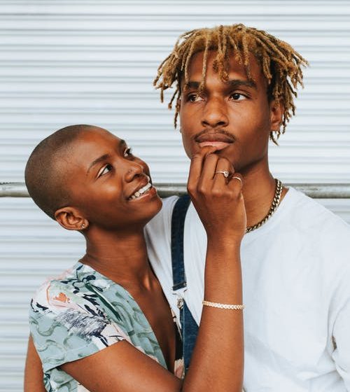 A black woman smiling while pinching the lower lip of her boyfriend