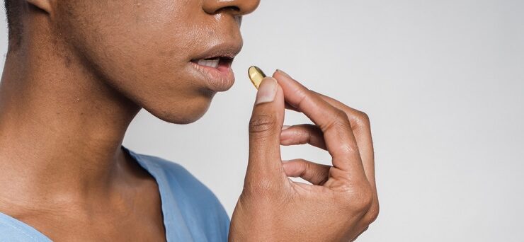 Black woman putting a birth control pill in her mouth