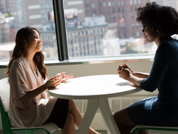 Two women seated at a round table chatting