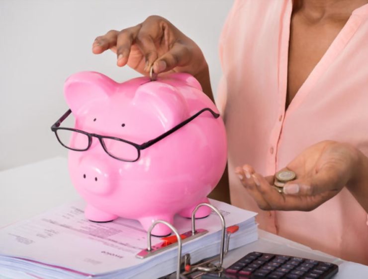 money saving tips image of a black woman putting coins into a piggy bank