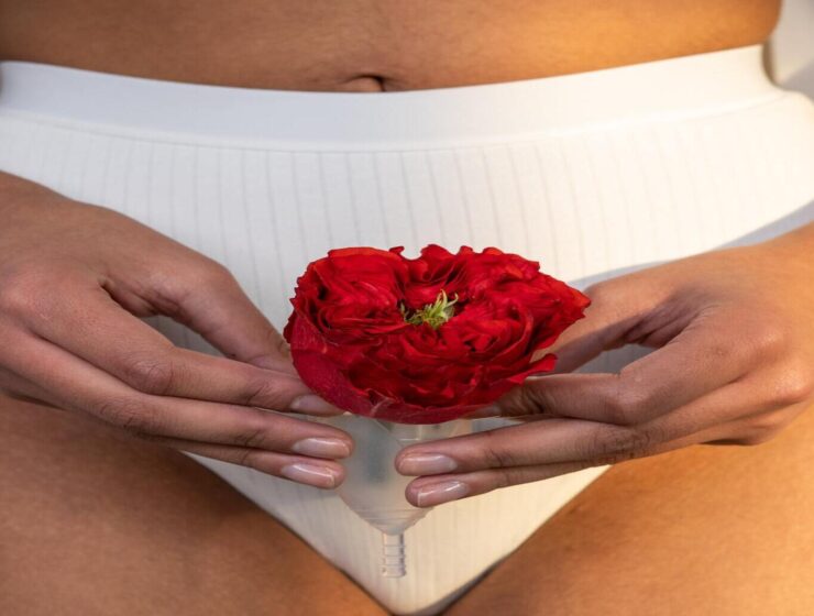 woman holding flower and period cup to symbolize fibroids