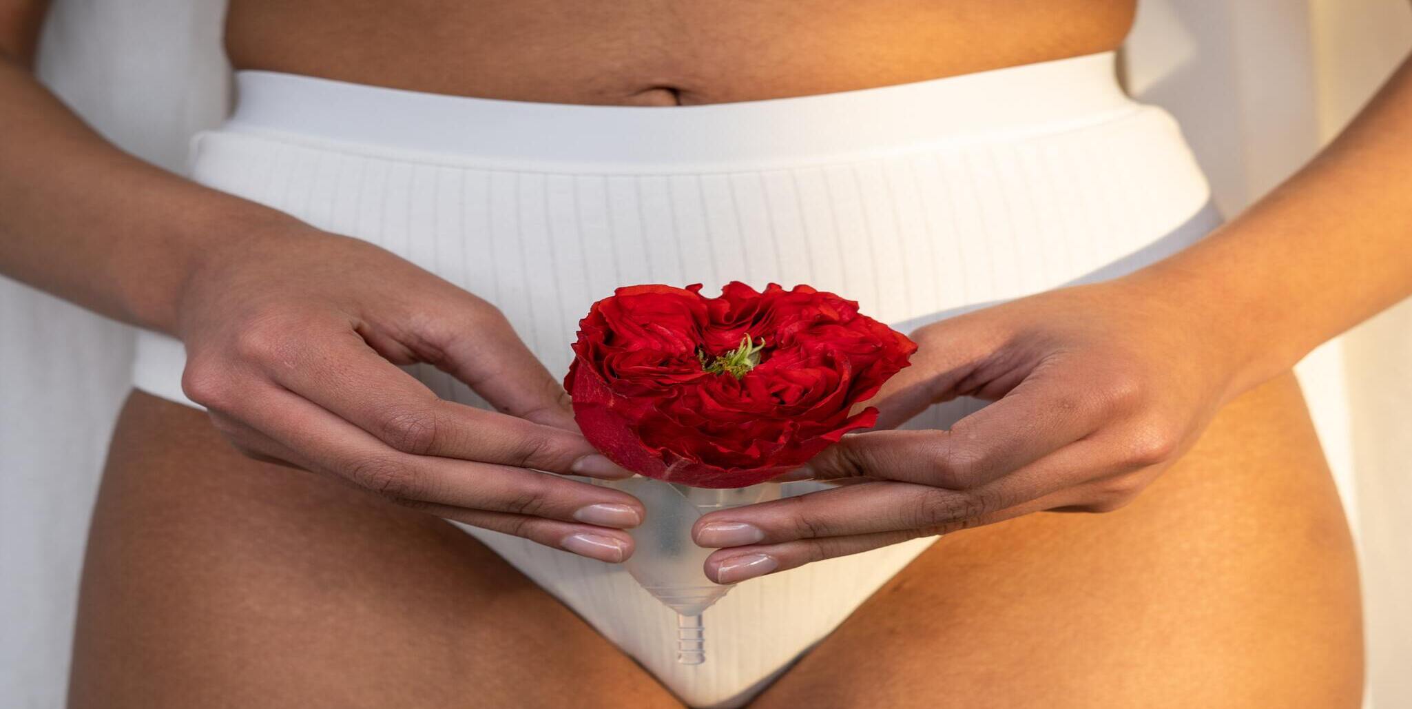 woman holding flower and period cup to symbolize fibroids