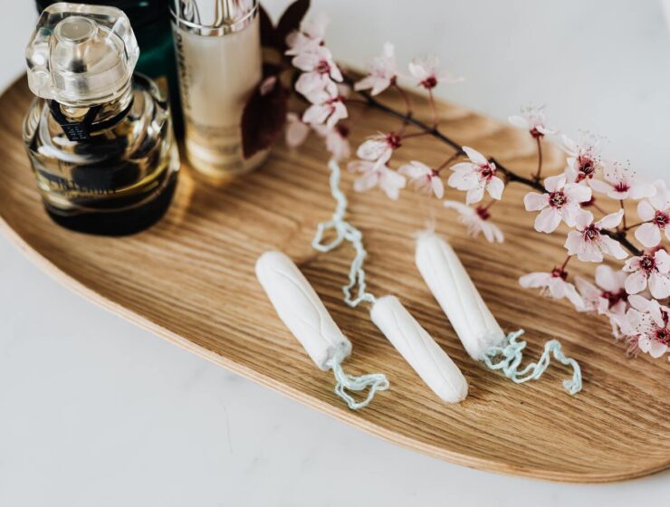 menstrual cramps - tampons, flowers and fragrance on a wooden tray