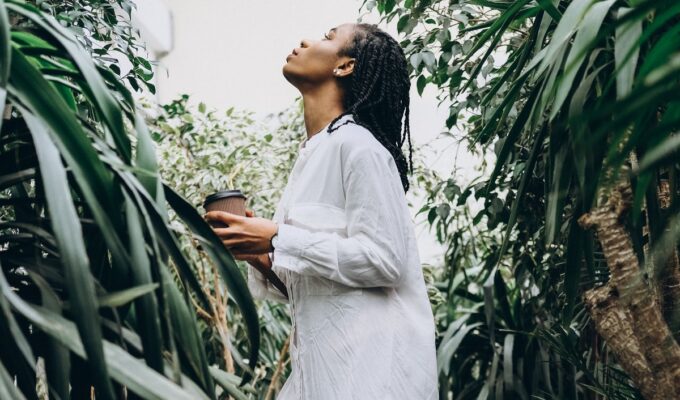 Spiritual Black woman looking up while surrounded by plants