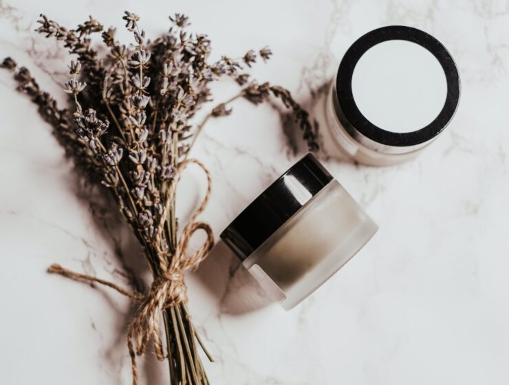 lavender plant next to two containers of cream