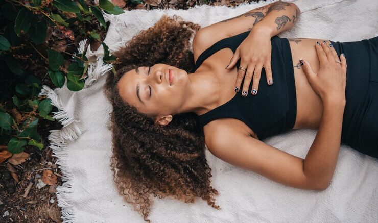 A Black woman lying on the ground touching her body