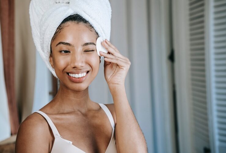 Black woman wiping her face practicing skin care tips