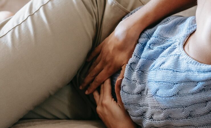 A woman with her hands on her abdomen in pain from urinary tract infections