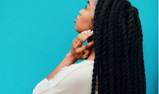 Black woman holding her neck and wearing braids