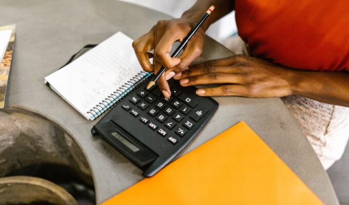 Black woman pressing a calculator as she works on financial independence
