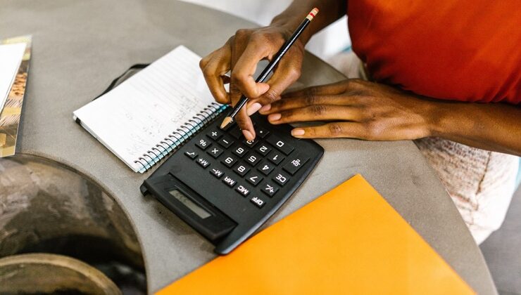 Black woman pressing a calculator as she works on financial independence