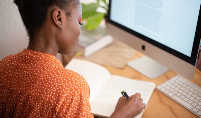 Black woman writing at a desk practicing goal setting