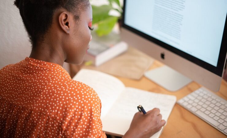 Black woman writing at a desk practicing goal setting