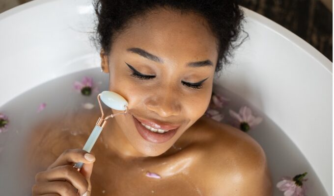 Black woman using a jade roller to massage her face