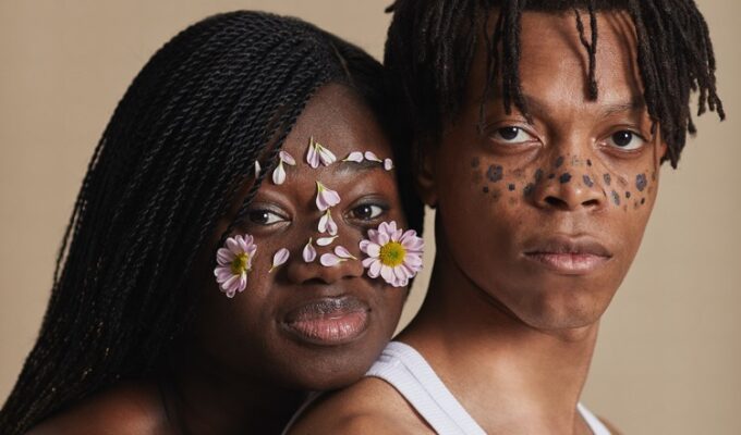 Cultural influences in relationship displayed by a black couple with marks and flowers on their faces.