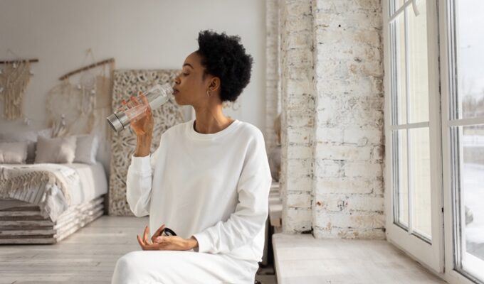 Black woman practicing morning rituals by drinking water in the morning