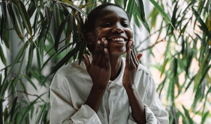 A black woman applying something to her face to aid healthy aging