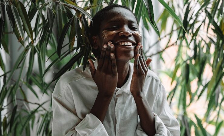 A black woman applying something to her face to aid healthy aging