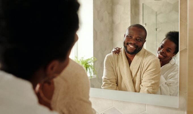 Black couple smiling at each other in the mirror practicing healthy sexuality