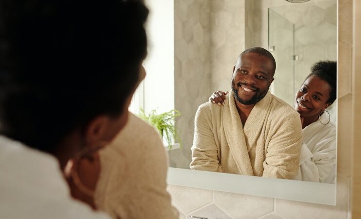 Black couple smiling at each other in the mirror practicing healthy sexuality