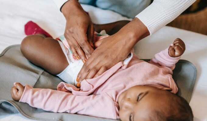 a woman's hand snapping a diaper on a baby, demonstrating care for special needs children