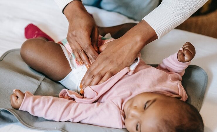 a woman's hand snapping a diaper on a baby, demonstrating care for special needs children