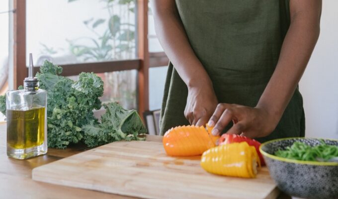A black woman practicing meal planning by cutting vegetables.