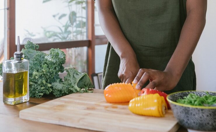 A black woman practicing meal planning by cutting vegetables.