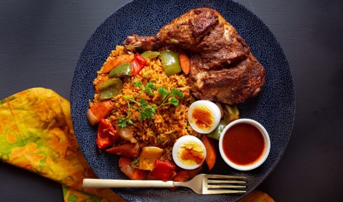 a place of jollof rice with chicken, vegetables and boiled egg.