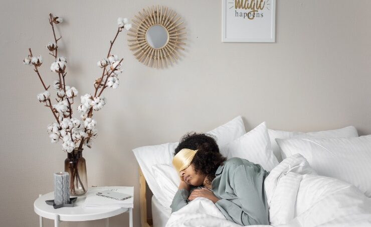 A Black woman laying in bed with eye covers while dealing with sleep anxiety