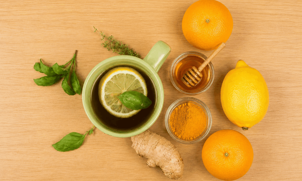 Herbal tea with lemon, honey, turmeric, and ginger on a wooden table representing natural remedies for common cold.