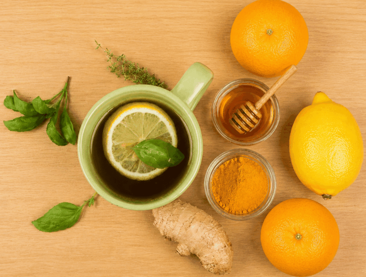 Herbal tea with lemon, honey, turmeric, and ginger on a wooden table representing natural remedies for common cold.