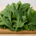 Fresh bitter leaf (Vernonia amygdalina) piled on a wooden chopping board