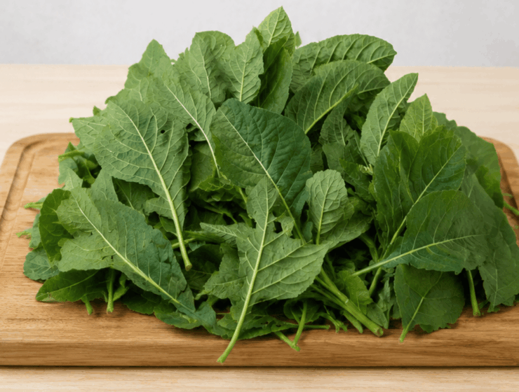 Fresh bitter leaf (Vernonia amygdalina) piled on a wooden chopping board