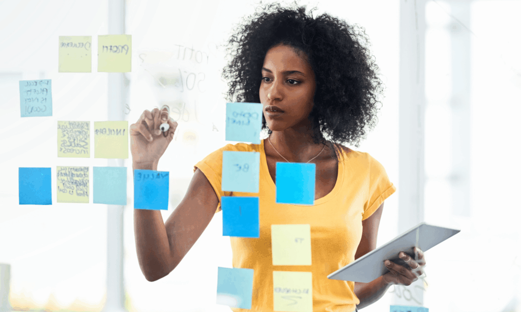 African woman planning her goals using sticky notes during a mid-year goal review session.