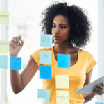 African woman planning her goals using sticky notes during a mid-year goal review session.