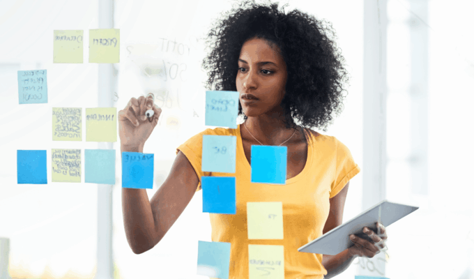 African woman planning her goals using sticky notes during a mid-year goal review session.