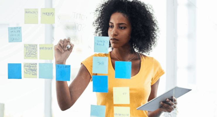 African woman planning her goals using sticky notes during a mid-year goal review session.