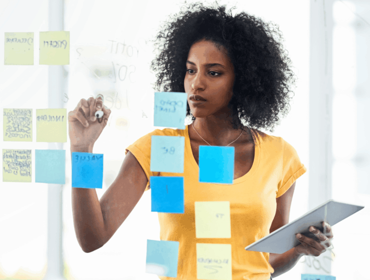 African woman planning her goals using sticky notes during a mid-year goal review session.