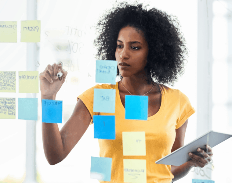 African woman planning her goals using sticky notes during a mid-year goal review session.
