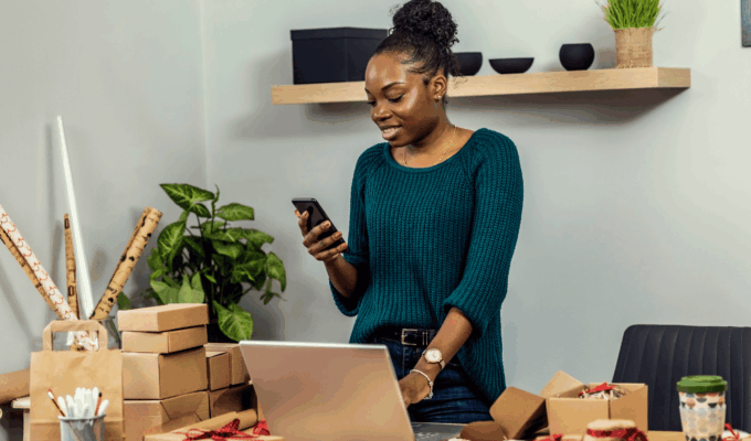 African female entrepreneur managing customer orders from home while applying small business tips to improve productivity.