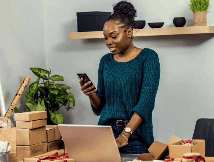African female entrepreneur managing customer orders from home while applying small business tips to improve productivity.