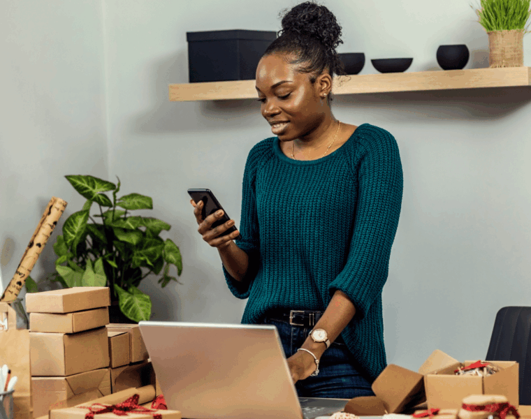 African female entrepreneur managing customer orders from home while applying small business tips to improve productivity.