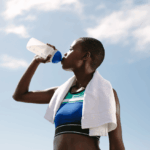 African woman drinking water after a workout, highlighting the benefits of drinking water for hydration and recovery.