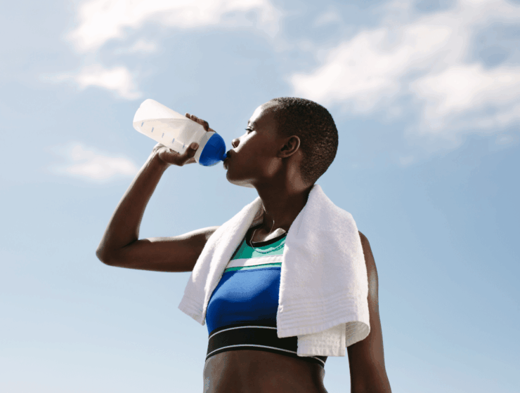 African woman drinking water after a workout, highlighting the benefits of drinking water for hydration and recovery.