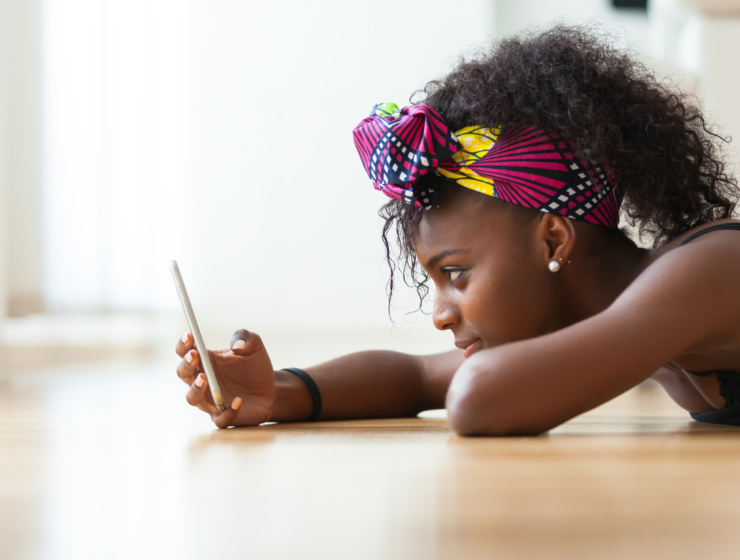 African woman lying on the floor checking her phone, illustrating one of the four attachment types.